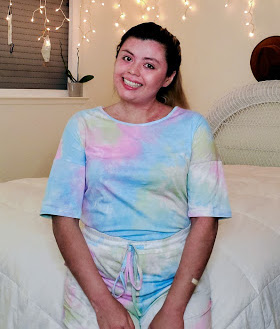 Daisy sits on her bed and smiles for a photo