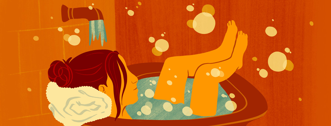 A woman takes a bubble bath and relaxes.