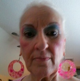 A selfie of Millie wearing eye shadow and large pink earrings