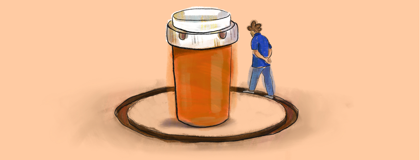 A person walks in a worn down path around a large prescription medicine bottle.