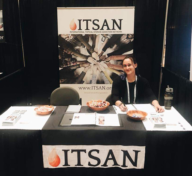 Briana Banos sitting at a table with signage for ITSAN.