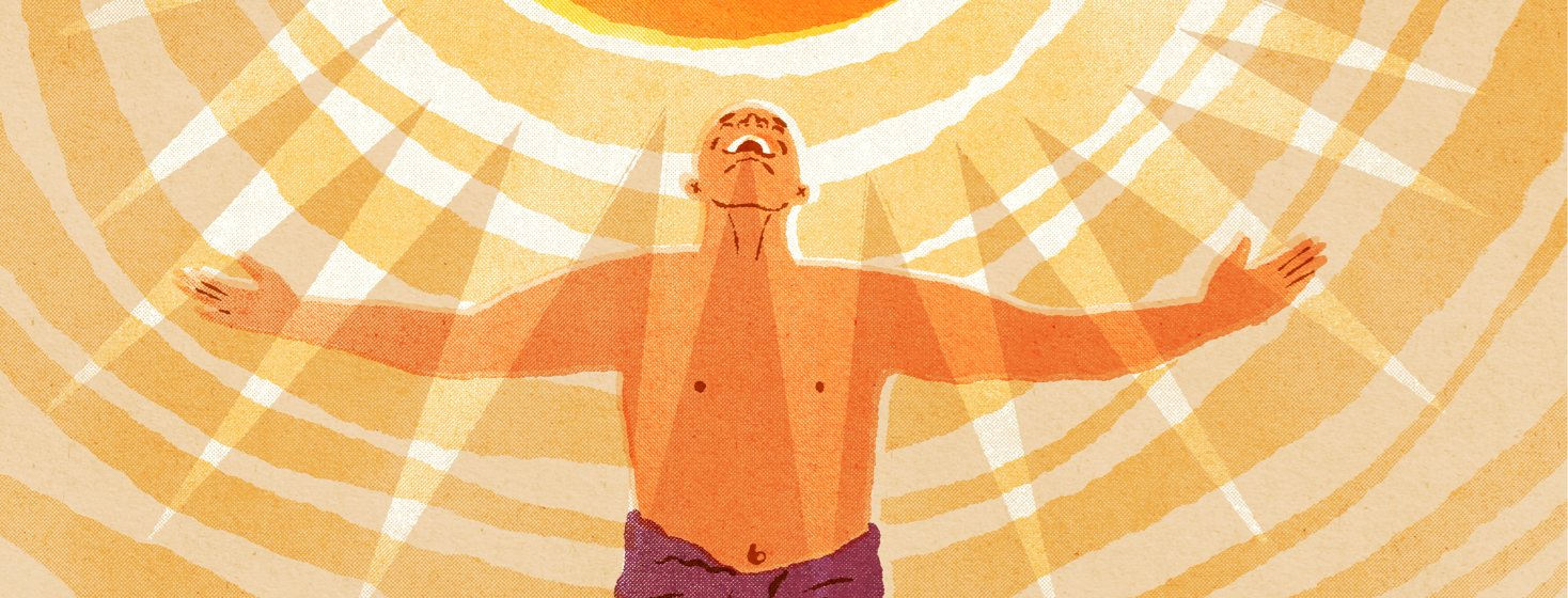 A man clothed in a spa towel holds his hands, happily, up to a light source above him.