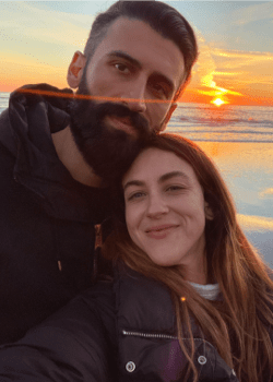 A selfie of a man and a woman in front of the ocean at sunset
