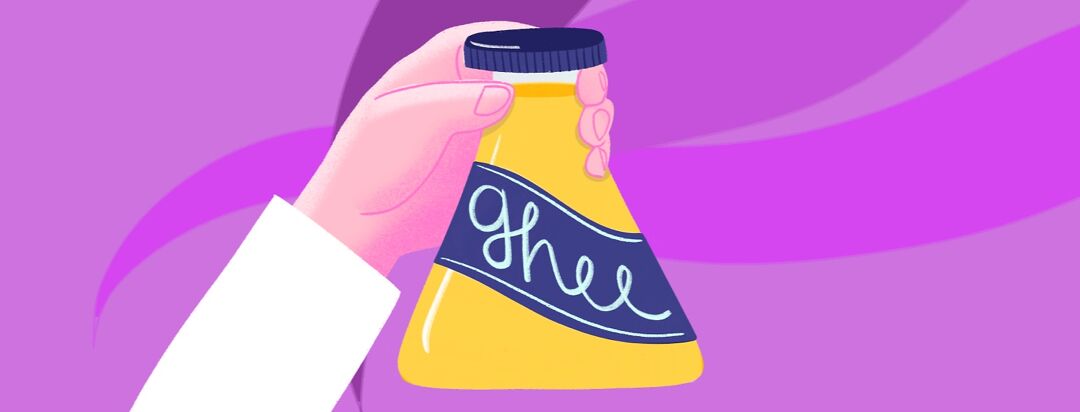 A hand holds a jar of ghee shaped like a beaker