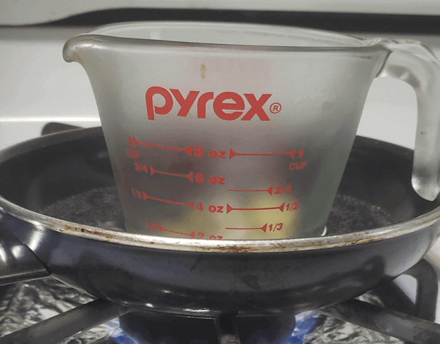 A glass pyrex with herbal oil and beeswax mixture